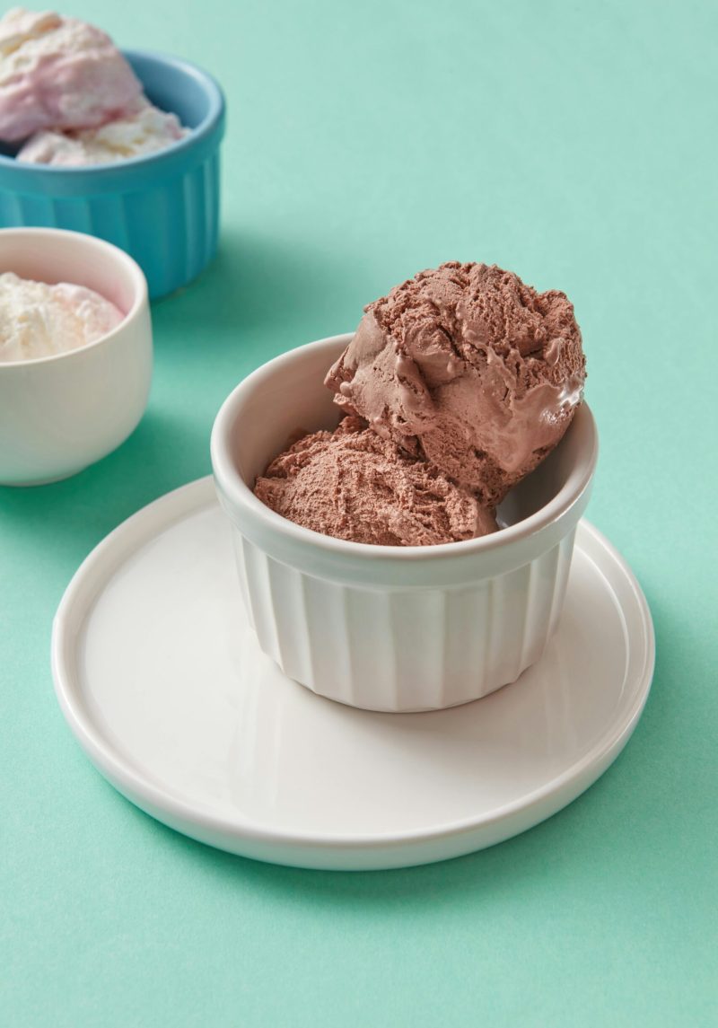 Delicious chocolate ice cream served in ramekins on a pastel backdrop.